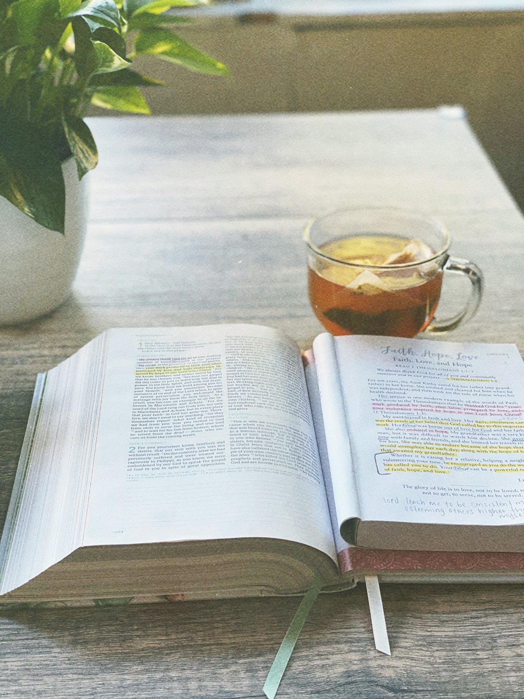 Otwarta Biblia i notatnik leżą na drewnianym stole.